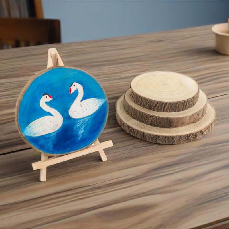 Decorative plate with swan design on a stand next to wooden coasters on a table.