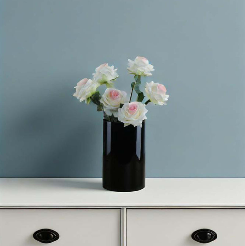 Black vase with white and pink flowers on a white surface against a blue wall