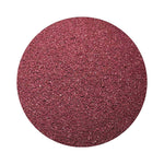 Burgundy colored sand arranged in a circular shape on a white background