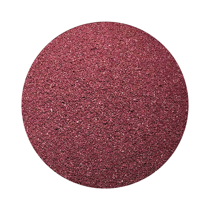 Burgundy colored sand arranged in a circular shape on a white background