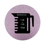 violet colored sand arranged in a circular shape on a white background colored sand in a circular shape with a measuring cup showing quantity.