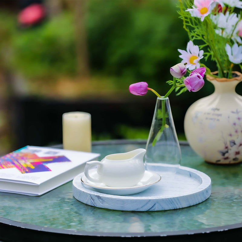 Table setting with a teacup, saucer, and decorative items on a marble tray outdoors.