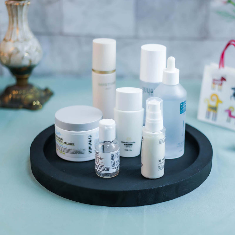 Collection of skincare products on a black tray with a blurred background