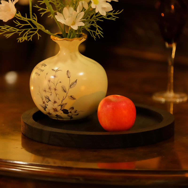 Decorative vase with flowers and an apple on a wooden surface