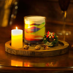 Decorative setup with candles and a small Christmas tree on a wooden board.