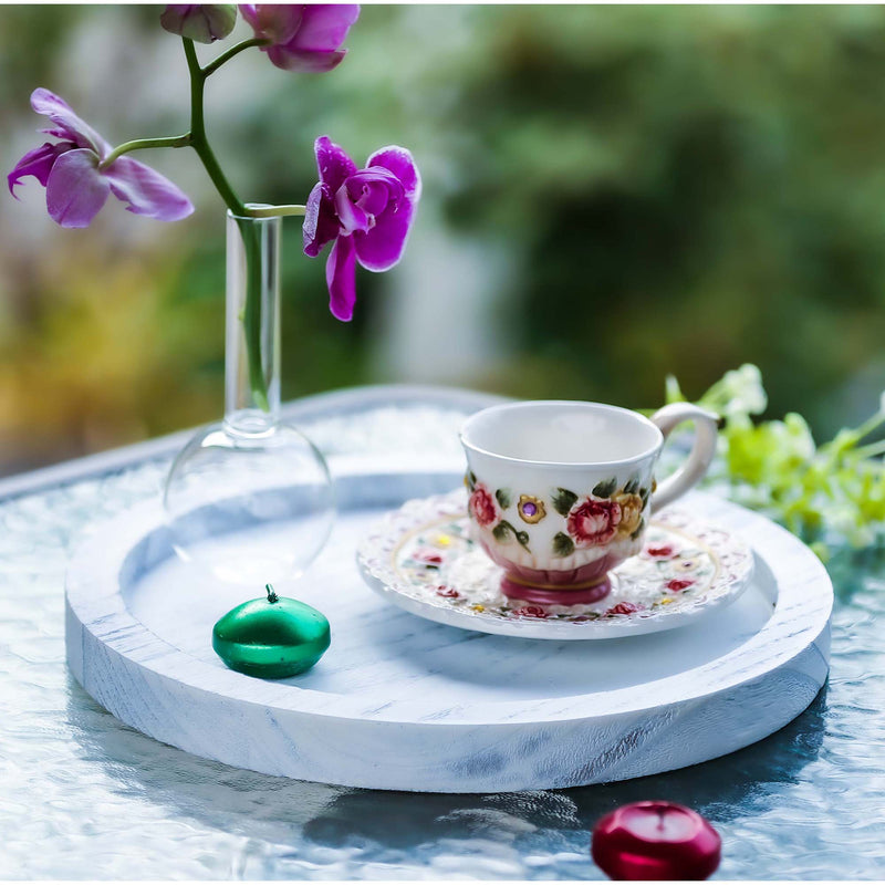 Teacup with floral design on a white marble tray, surrounded by purple flowers and greenery.