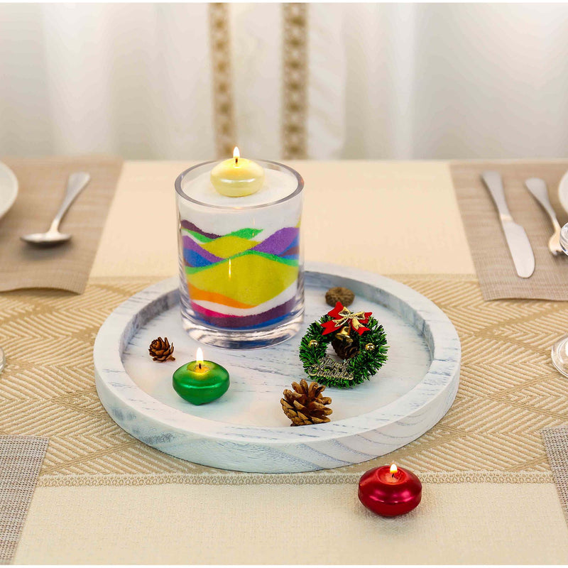 Decorative candles and small ornaments on a marble tray with a table setting in the background.