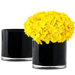 Black cylindrical vase with yellow flowers on a white background