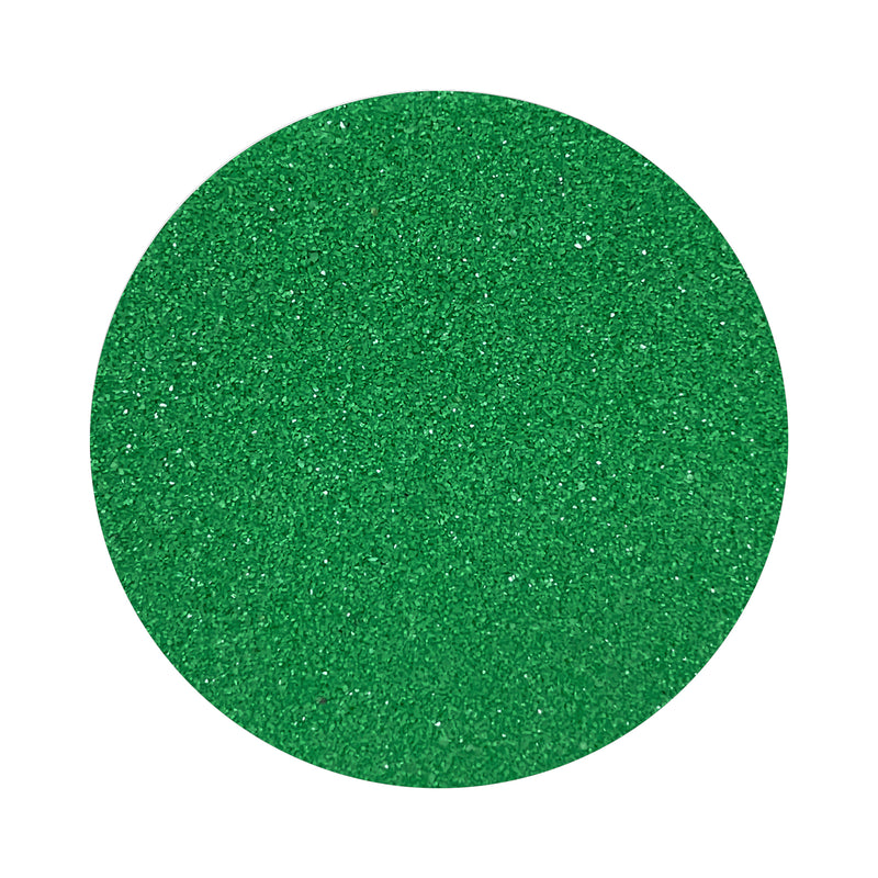 Dark green colored sand arranged in a circular shape on a white background