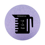 lavender purple colored sand arranged in a circular shape on a white background colored sand in a circular shape with a measuring cup showing quantity.