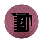 Wine colored sand arranged in a circular shape on a white background colored sand in a circular shape with a measuring cup showing quantity.