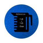 
Royal Blue colored sand arranged in a circular shape on a white background colored sand in a circular shape with a measuring cup showing quantity, all placed on a white background.