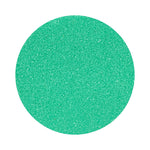 Turquoise colored sand arranged in a circular shape on a white background