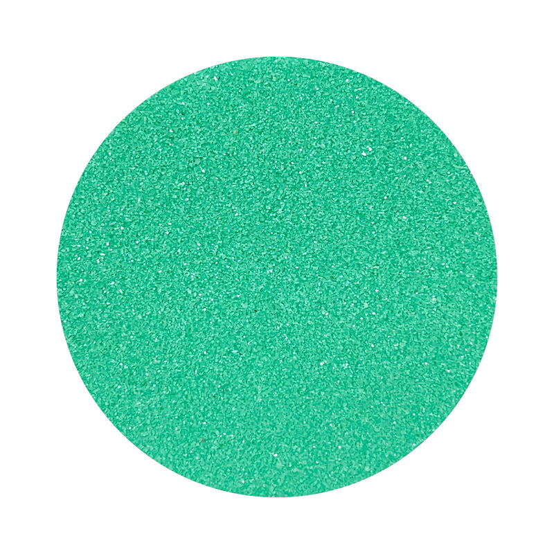 Turquoise colored sand arranged in a circular shape on a white background